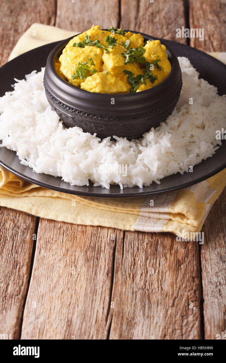 Indische Küche: Korma Hühnchen in Kokosnuss-Sauce und Basmati-Reis-Nahaufnahme auf dem Tisch. vertikale Stockfoto