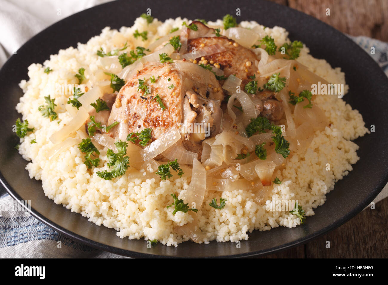 Westafrikanische Essen: Huhn Yassa und Couscous mit Zwiebeln auf einer Platte Makro. horizontale Stockfoto