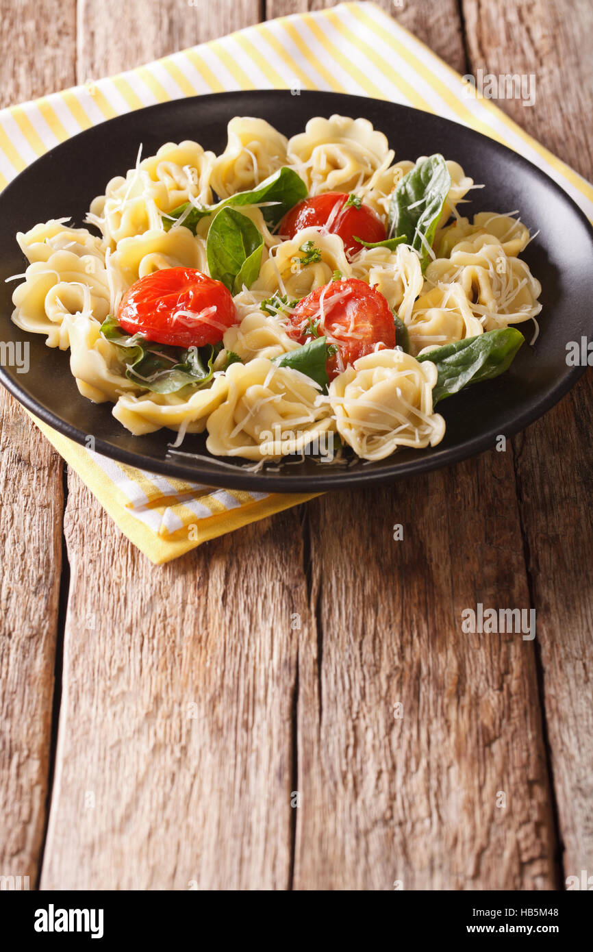 Leckere Tortellini mit Spinat, Tomaten und Käse auf einen Teller Nahaufnahme. Vertikal Stockfoto