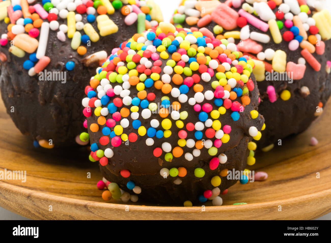 Selektiven Fokus auf süße Schokolade Cupcake mit bunten Streuseln in einer hölzernen Platte garniert Stockfoto