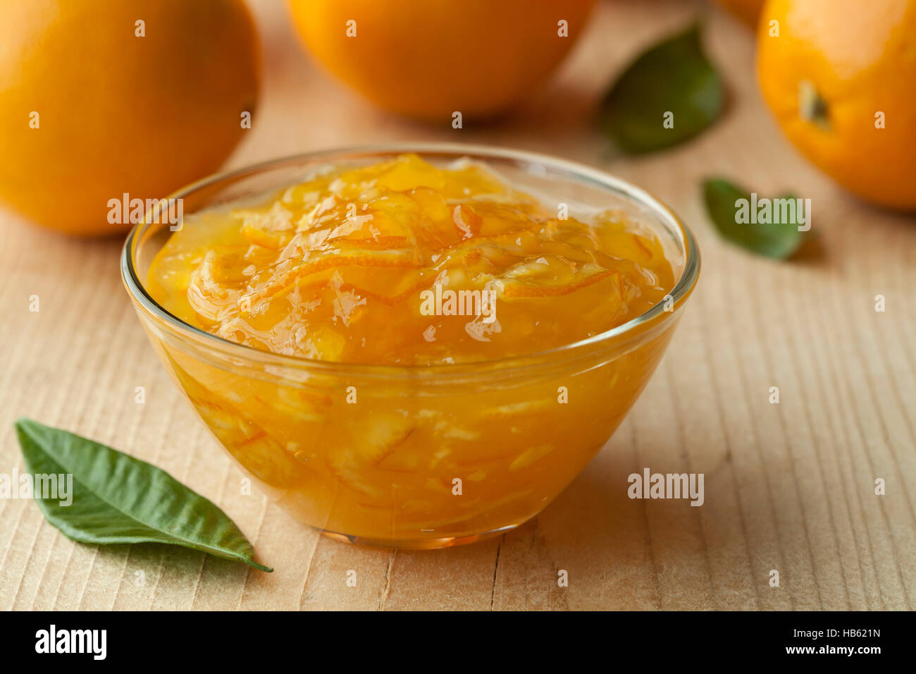 Schale mit hausgemachter Marmelade und frischen Orangen im Hintergrund Stockfoto