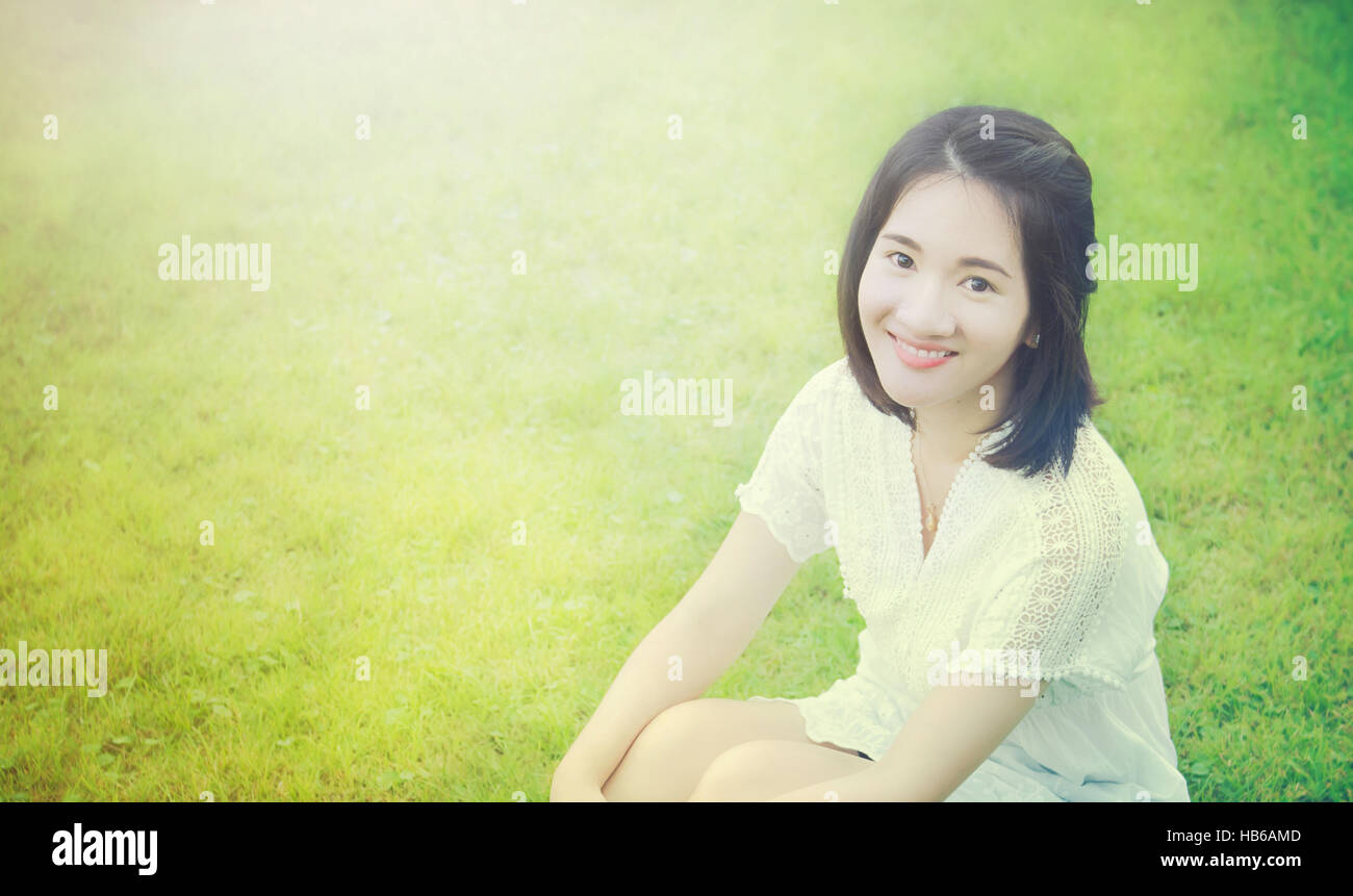 Porträtfoto des asiatischen Thai Mädchen mit Smiley-Gesicht im Garten mit Morgen Licht und Grass Hintergrund und leere Kopie Text Platz Stockfoto