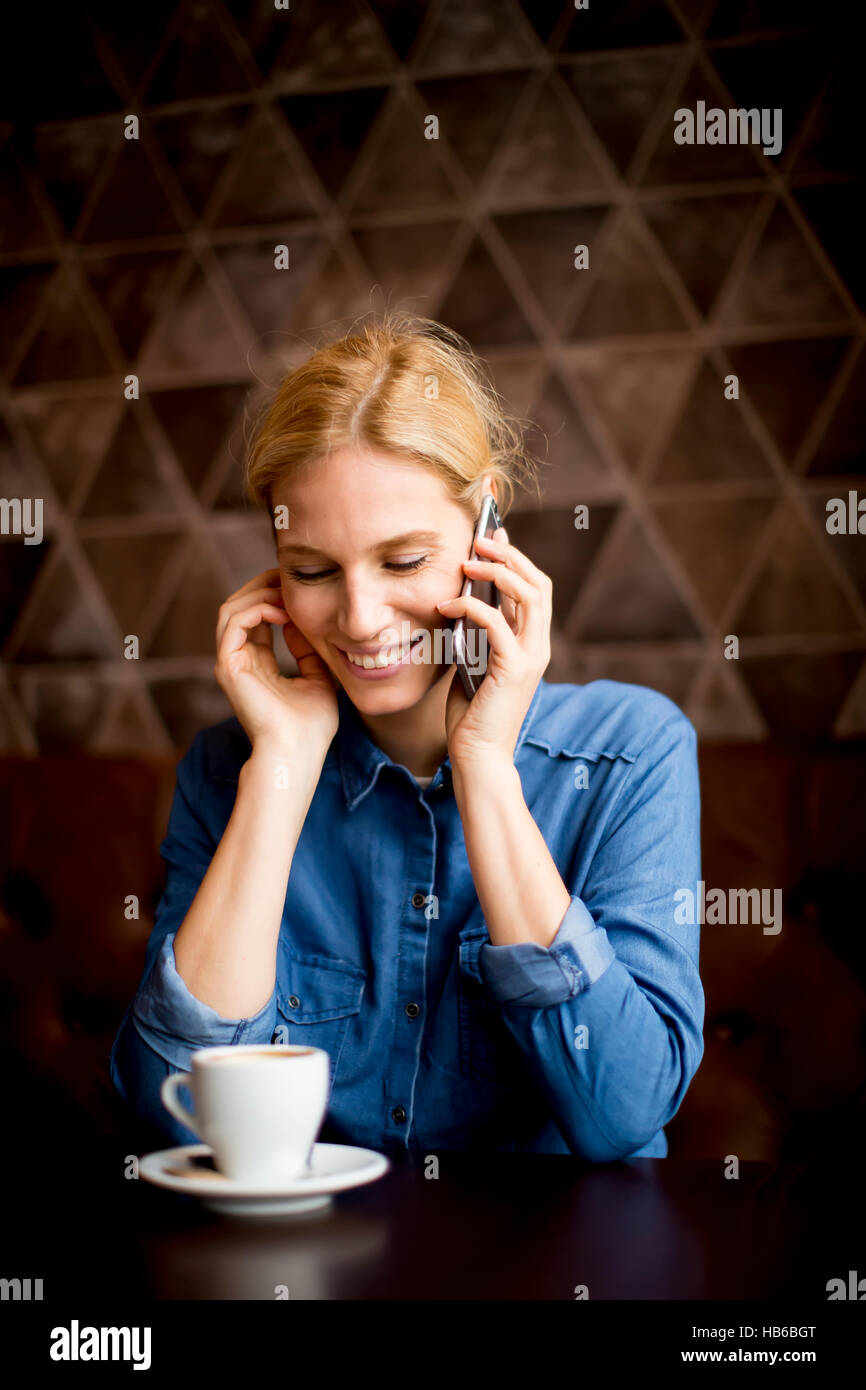 Junge Frau im Café sitzen, mit Telefon und trinken Kaffee Stockfoto