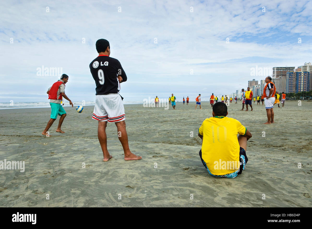 Menschen in Brasilien, Praia Grande, Sao Paulo, Brasilien - die Einheimischen spielen am Strand von Praia Grande eine Fußballpartie, die von Zuschauern beobachtet wird. Stockfoto