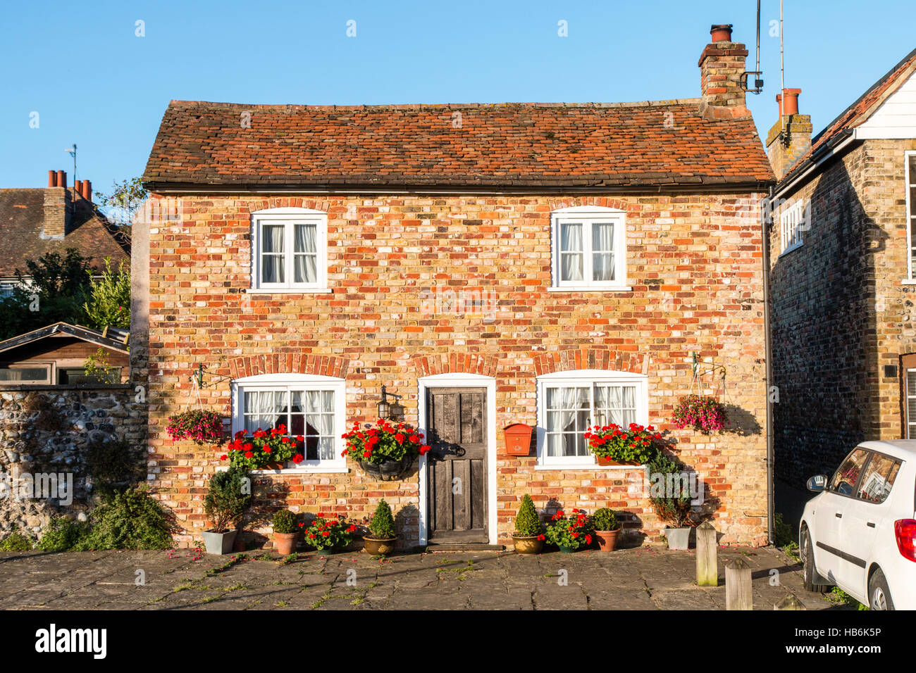 England, Sandwich. Ziemlich freistehende Doppel fronted Ziegelhaus mit Blumenkästen mit roten Blüten außerhalb. Blauer Himmelshintergrund. Stockfoto