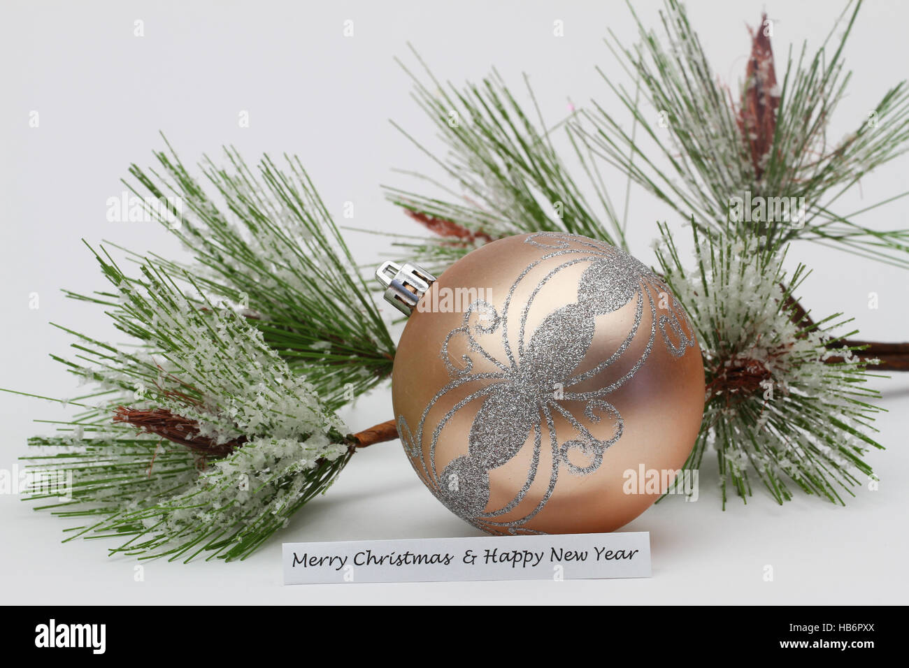 Frohe Weihnachten und Happy New Year Karte Farbe Creme Christbaumkugel mit Schnee bedeckt Kiefer Stockfoto