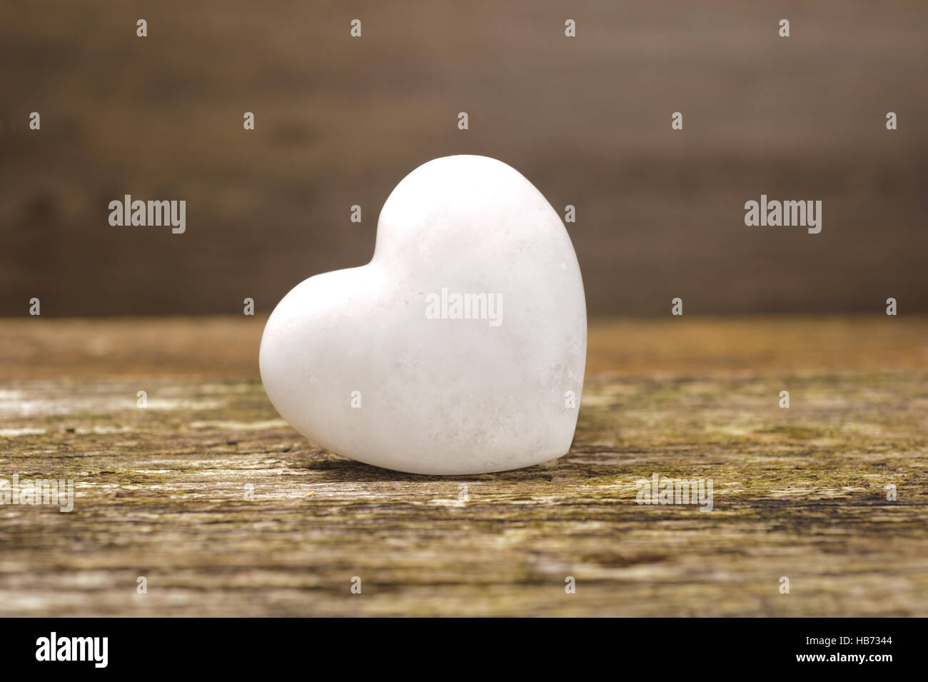 Weißes Herz aus Stein gemacht auf Holzbrett Stockfoto