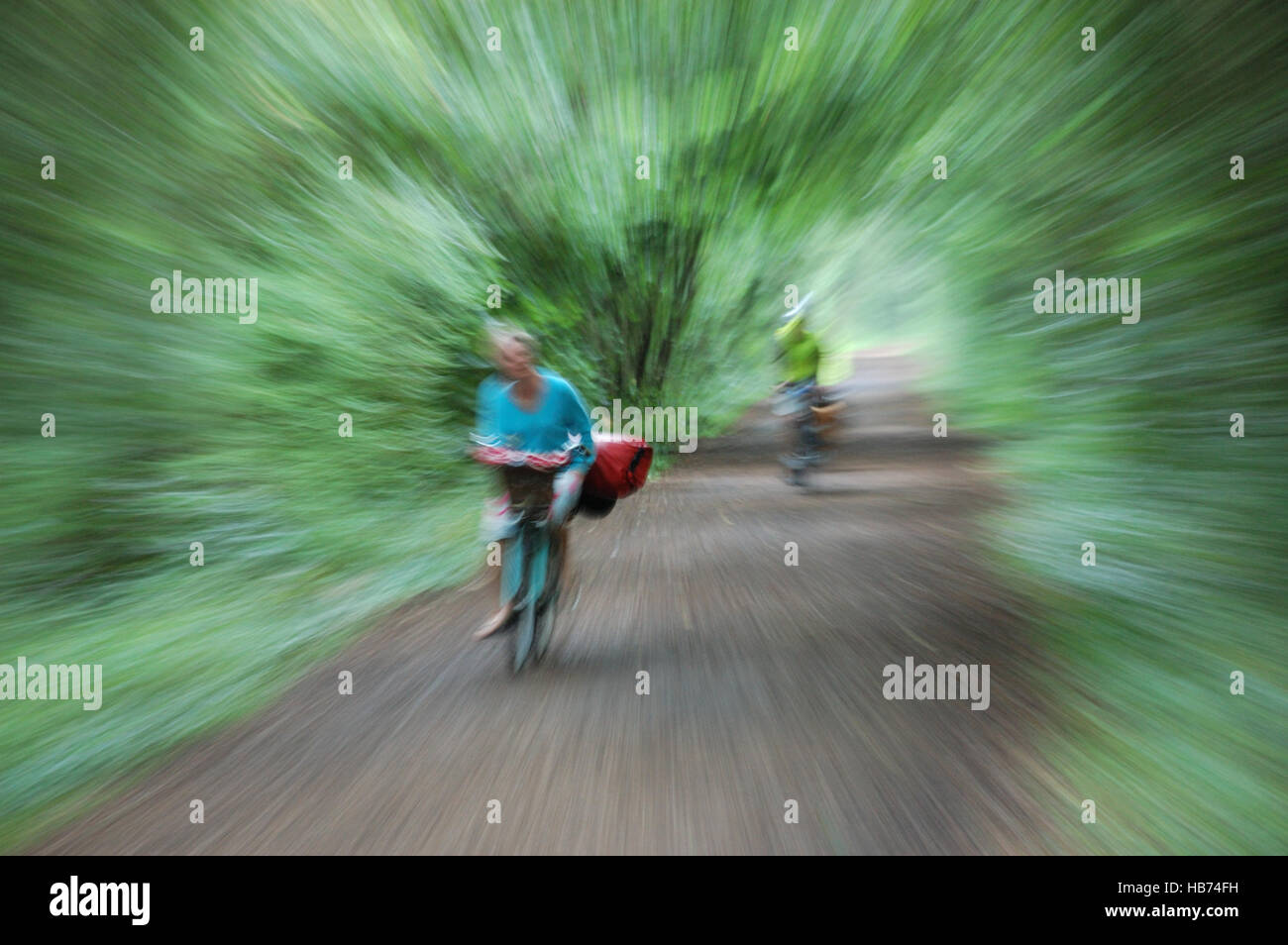 Zwei Radfahrer ein Mann und eine Frau auf einem Radweg genommen mit einer langen Belichtungszeit während zoomen, den Eindruck von Geschwindigkeit zu geben. Stockfoto
