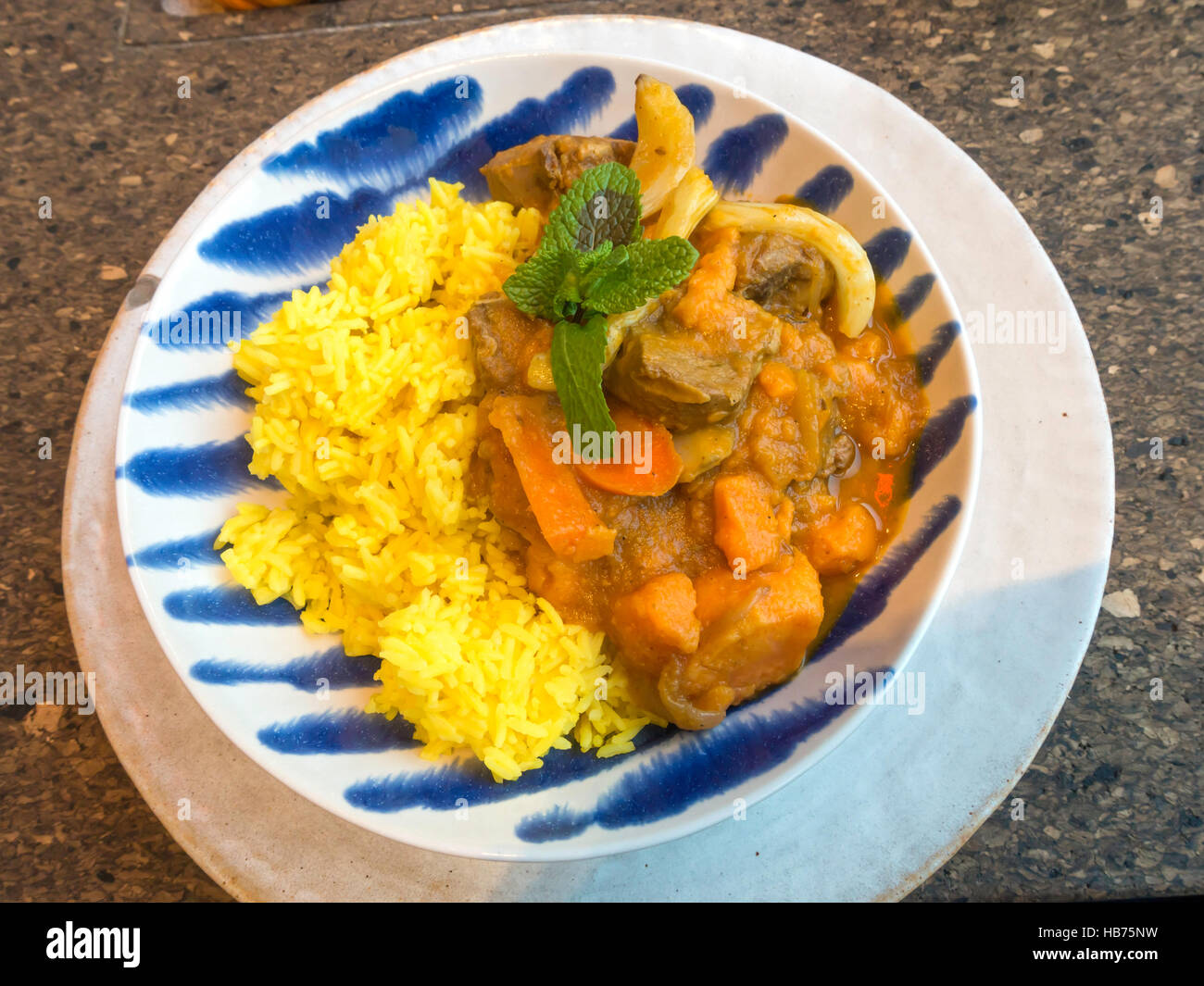 Eine Schüssel mit Lammcurry serviert mit Safranreis Karotten und Kürbis Stockfoto