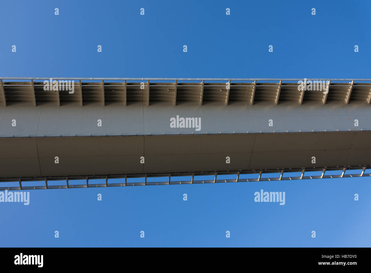 Skurrile aber interessante Aufnahme von der Unterseite eines Teils der Brücke suchen, kantig und moderne vor einem strahlend blauen Himmel Stockfoto