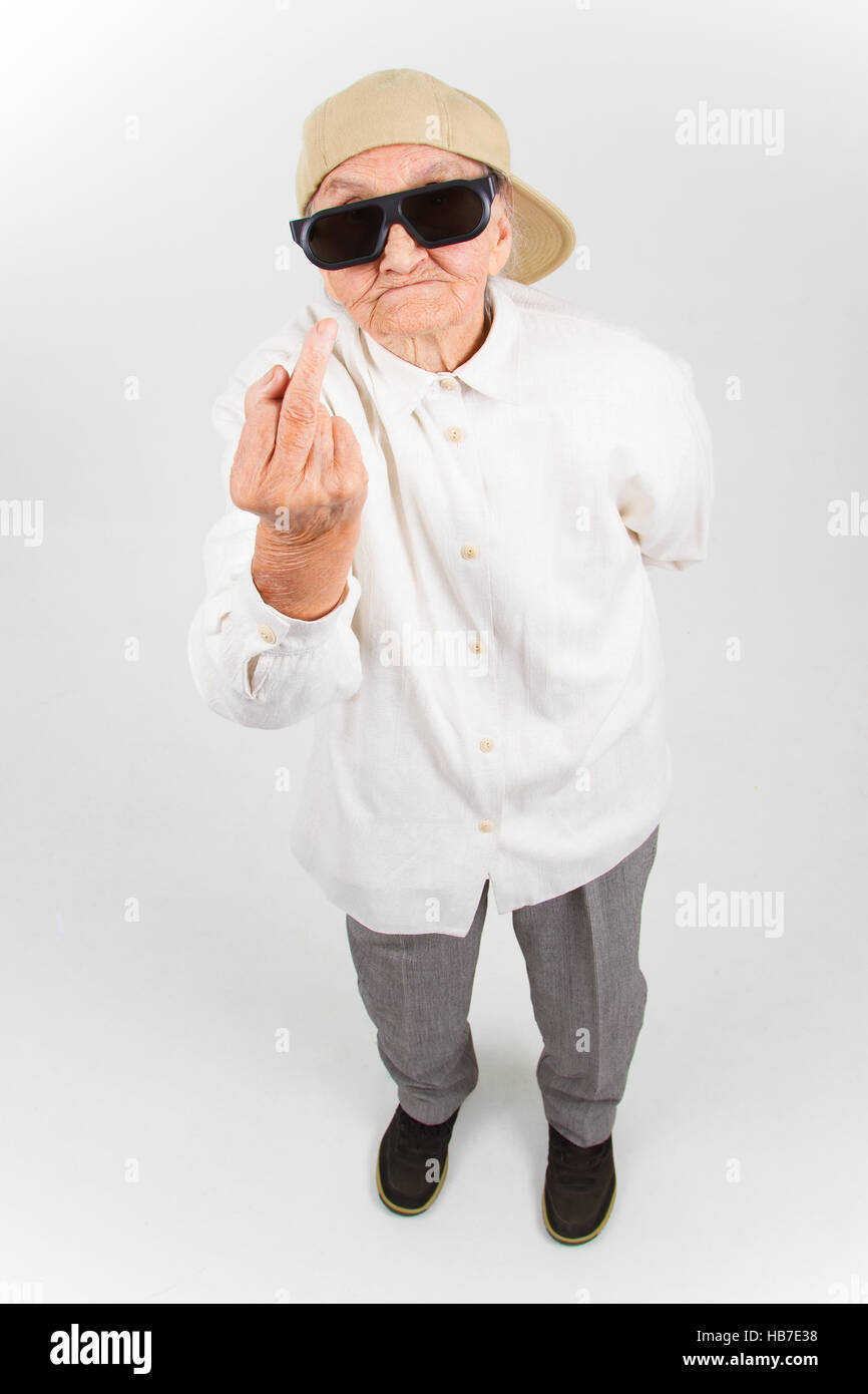Lustige Oma Studioportrait tragen Brillen und Baseball-Cap, den f-Finger zeigt, isoliert auf weiss Stockfoto