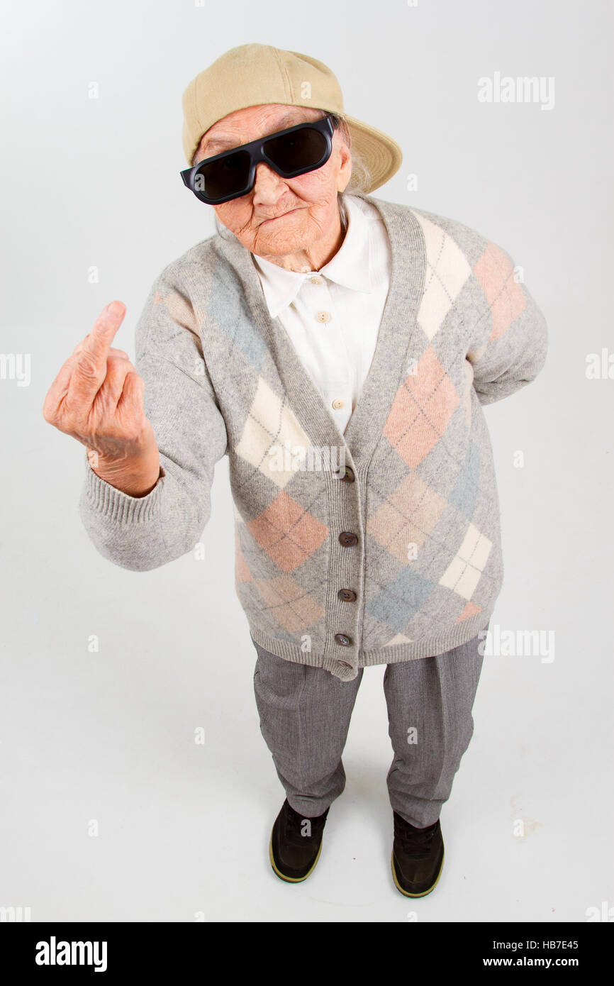 Lustige Oma Studioportrait tragen Brillen und Baseball-Cap, den f-Finger zeigt, isoliert auf weiss Stockfoto