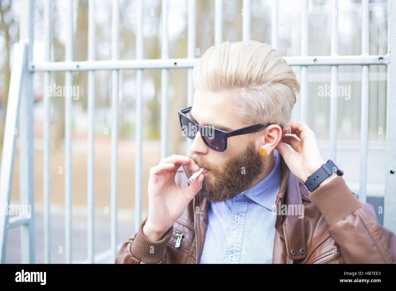 Hipster-Mann in einen verbotenen Bereich in der Öffentlichkeit rauchen. Stockfoto