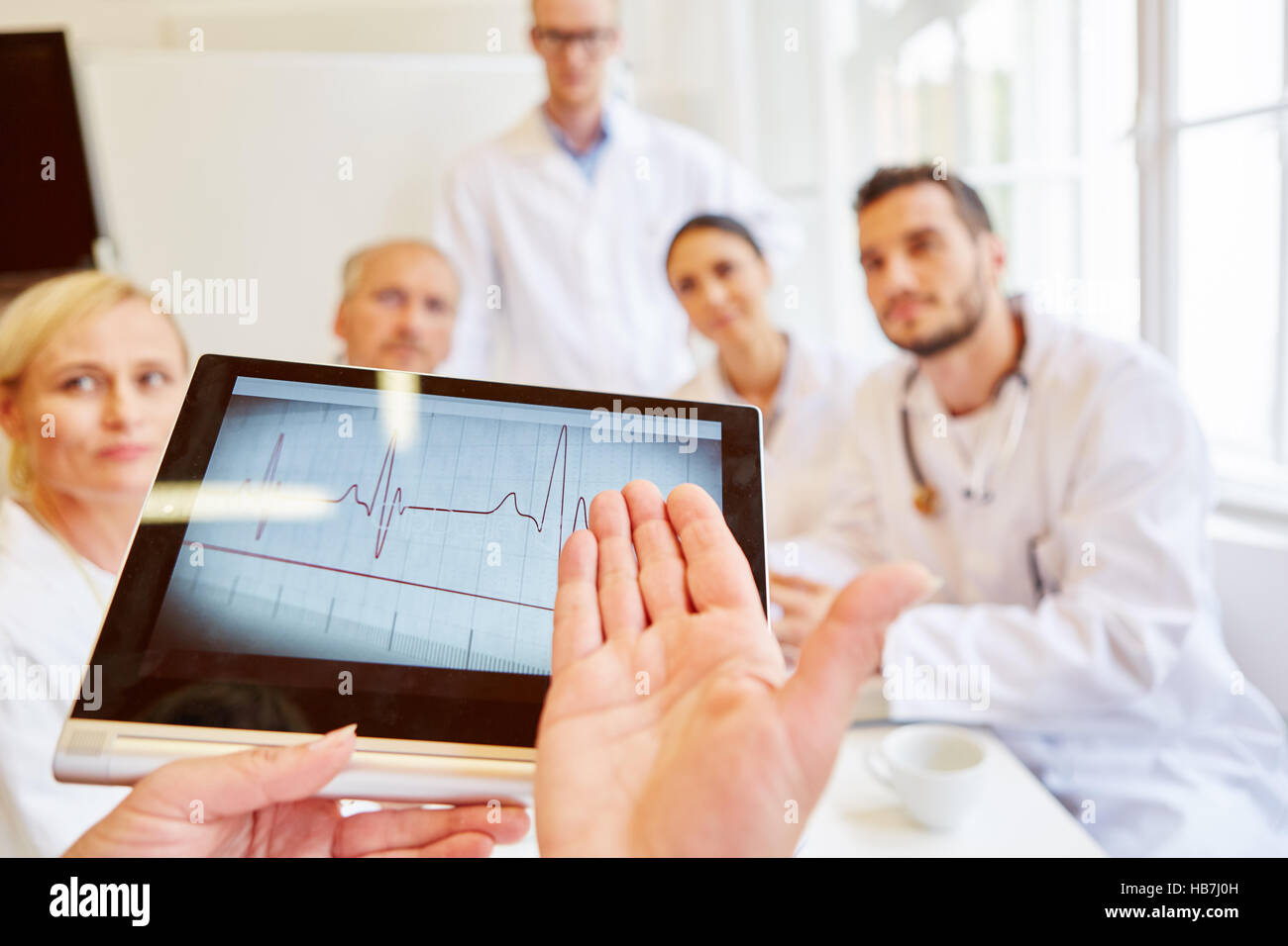 Elektrokardiogramm auf Tablet-Computer und Gruppe von Ärzten reden, ECG Stockfoto