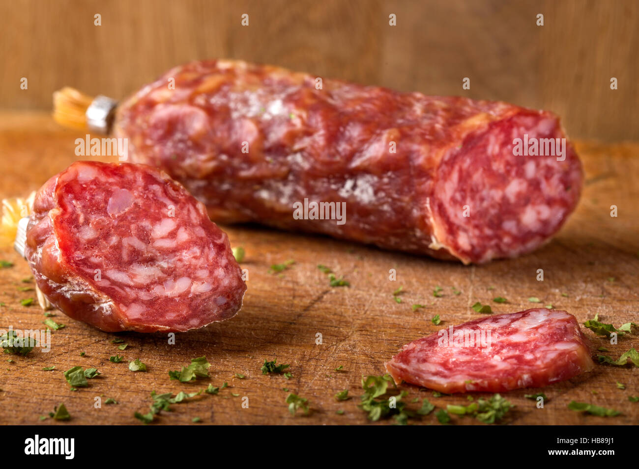 Nahaufnahme von italienischer Salami auf Holzbrett mit Kräutern Stockfoto