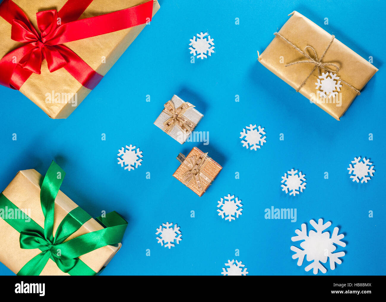Flache Laien Konzept der Weihnachtsartikel auf a blaue Tabelle. Zusammensetzung enthält Dekorationen, Schneeflocken, Beeren und Zweigen mit Geschenken. Stockfoto