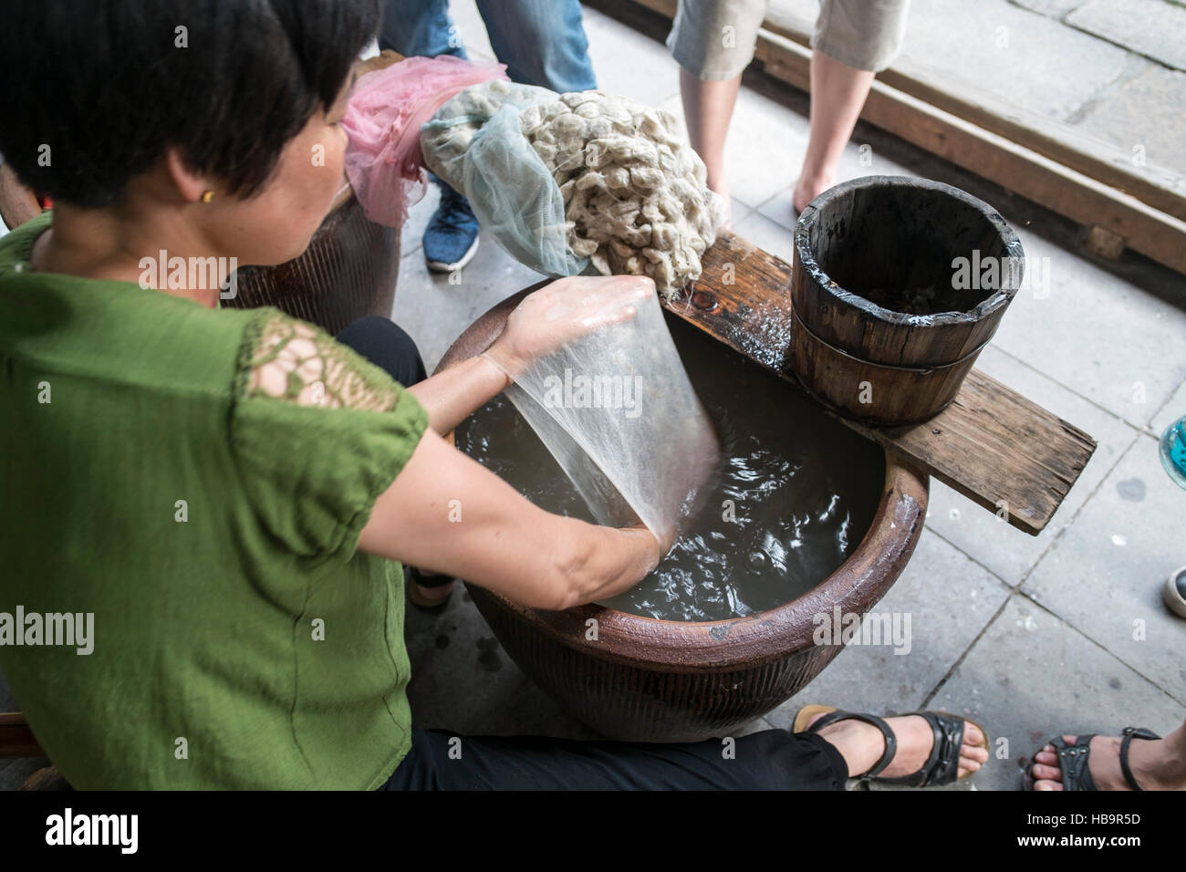 Frau ernten die seidenen Fäden nach dem Erwärmen der Kokons. Wuzhen, China Stockfoto