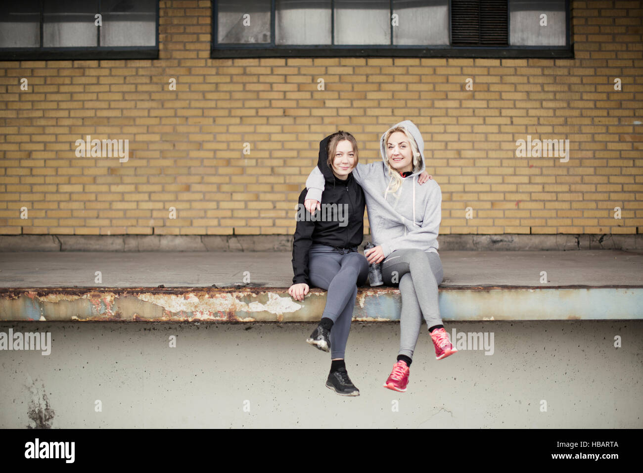 Porträt von zwei weibliche Läufer Freunde sitzen auf Lager-Plattform Stockfoto