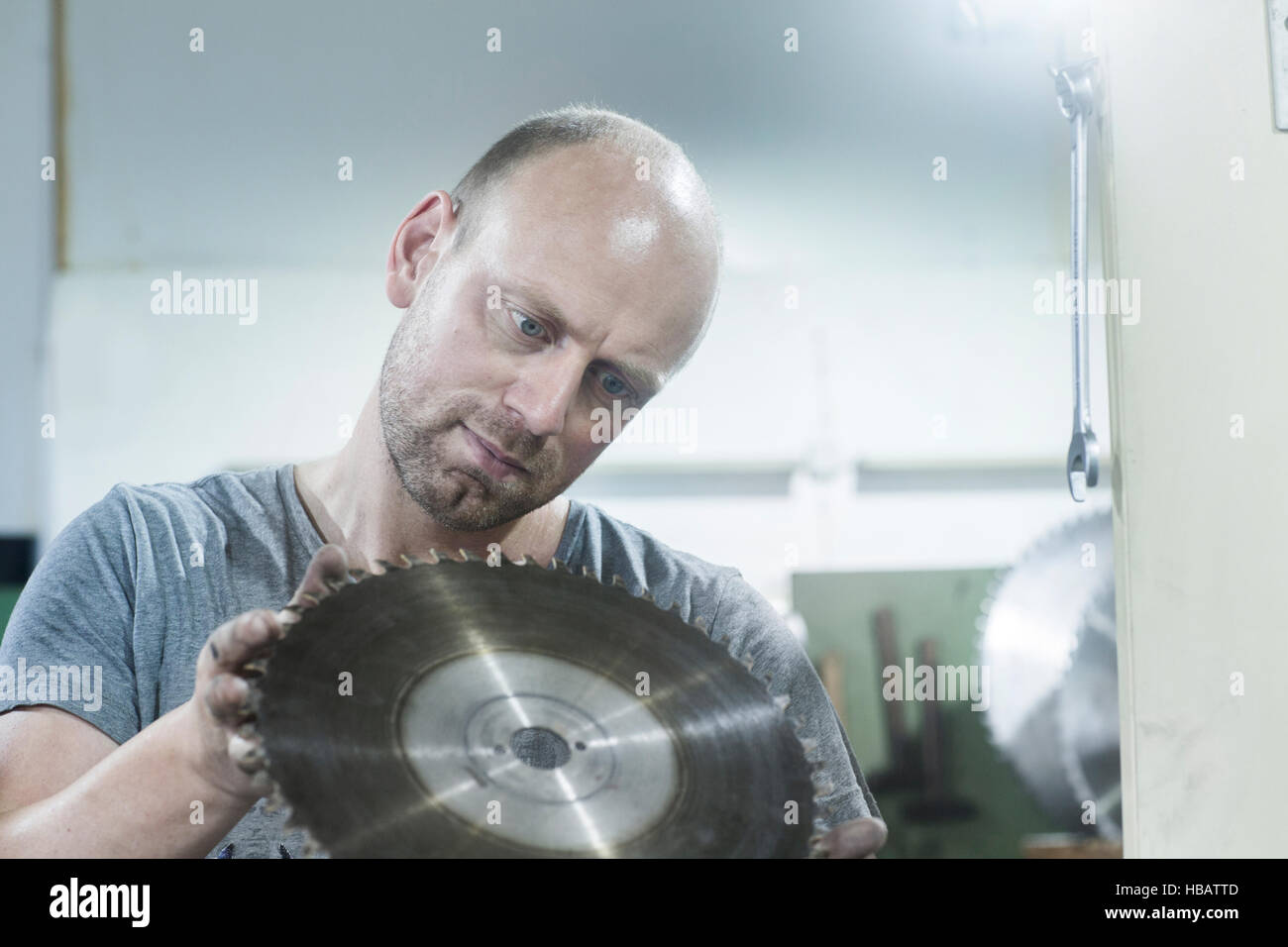 Mann überprüfen rotierende Klinge auf Schleifmaschine Stockfoto