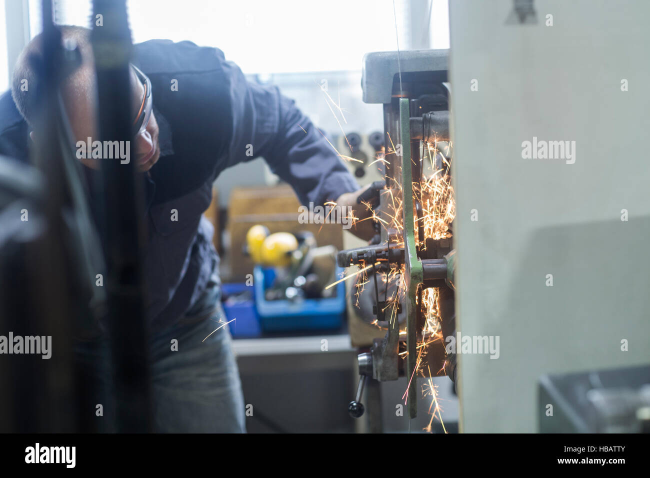 Mann, die Überwachung der Schleifmaschine in Werkstatt Stockfoto