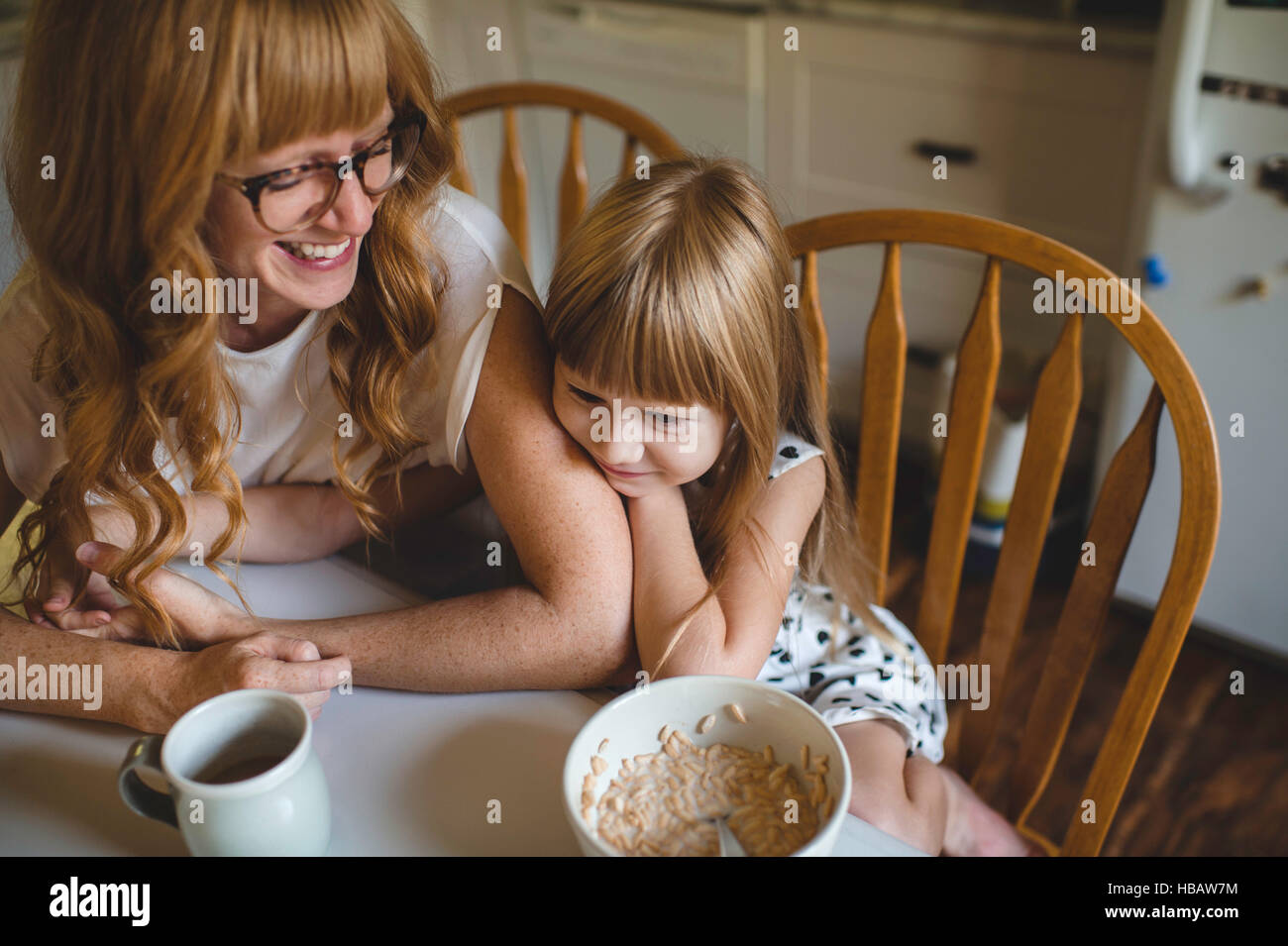 Mutter und Tochter kuscheln am Frühstückstisch Stockfoto