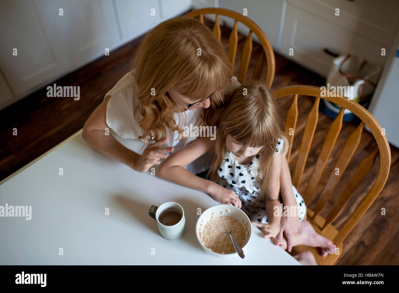 Mutter und Tochter kuscheln am Frühstückstisch Stockfoto