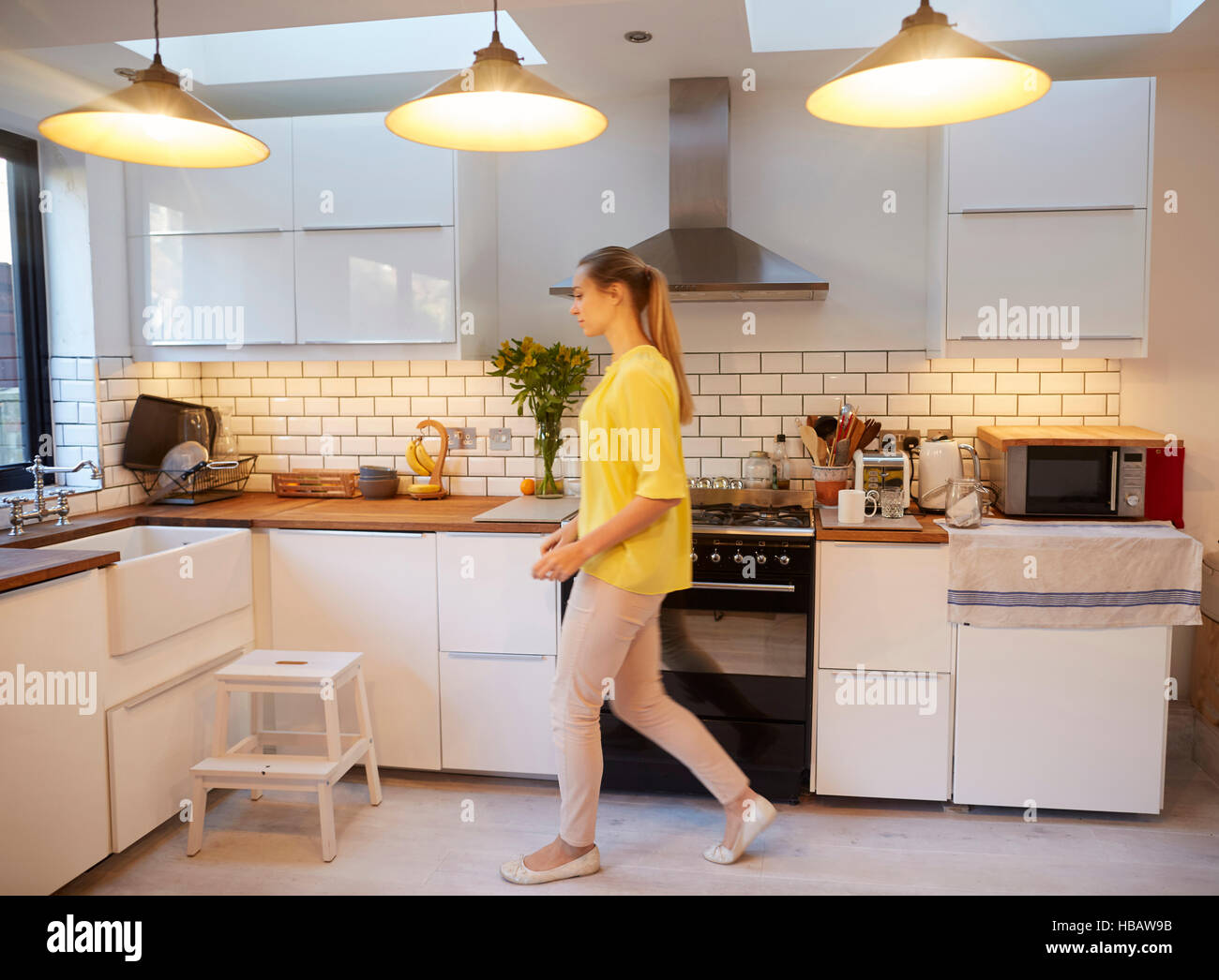 Mitte erwachsenen Frau zu Fuß in stilvollen Küche Stockfoto