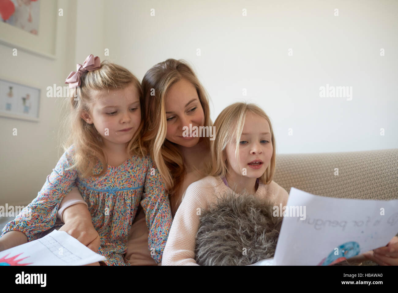 Mitte erwachsenen Frau betrachten Zeichnungen mit Töchtern im Wohnzimmer Stockfoto