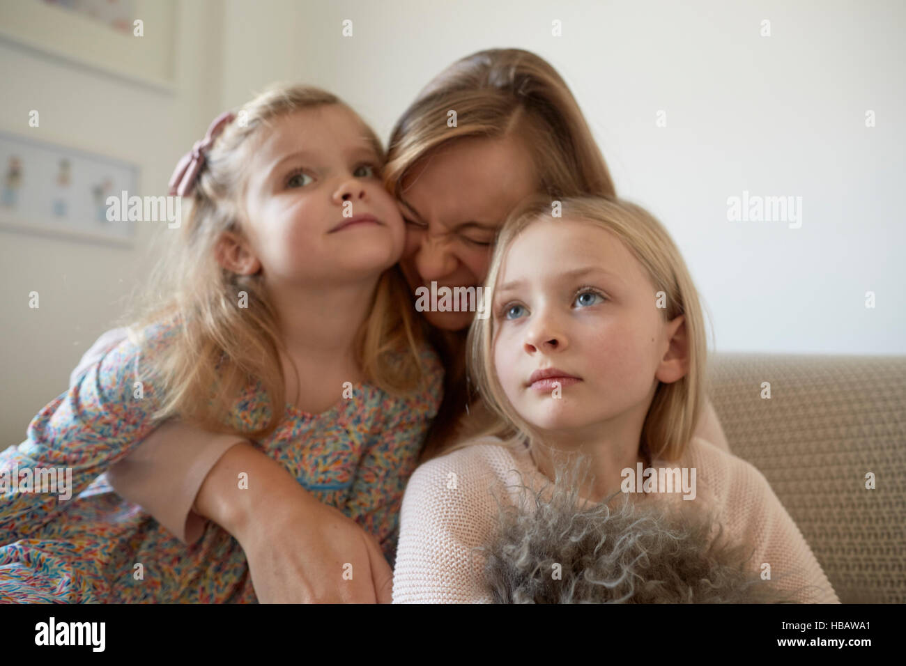 Mitte Erwachsene Frau umarmt Töchter im Wohnzimmer Stockfoto