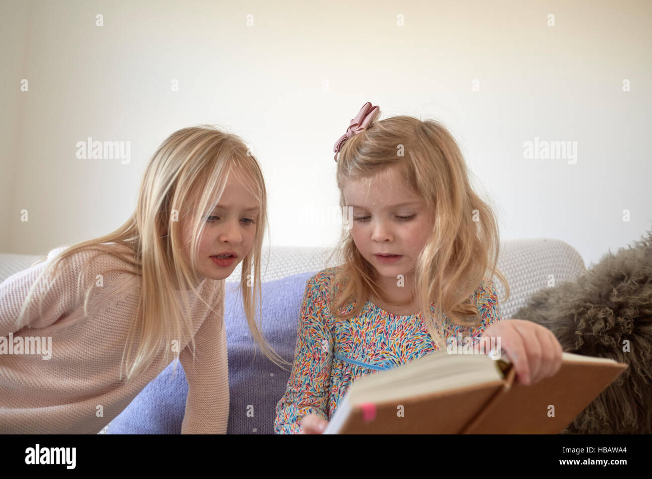 Mädchen und ihre Schwester im Wohnzimmer lesen Stockfoto