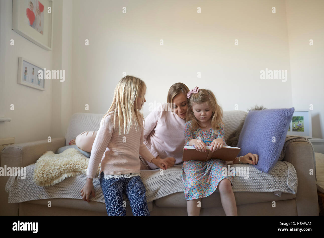 Mitte Erwachsene Frau und Töchter lesen Märchenbuch auf sofa Stockfoto