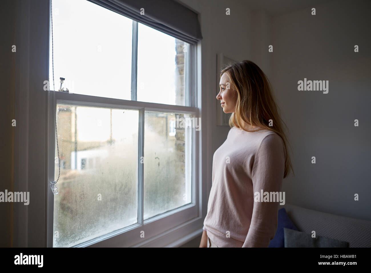 Mitte Erwachsene Frau blicken heraus durch Schlafzimmerfenster Stockfoto
