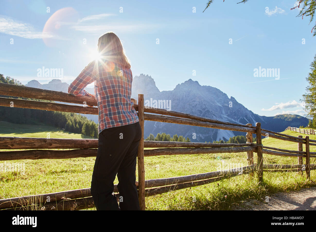 Reife Frau gelehnt Zaun mit Blick auf sonnenbeschienenen Dolomiten, Sexten, Südtirol, Italien Stockfoto