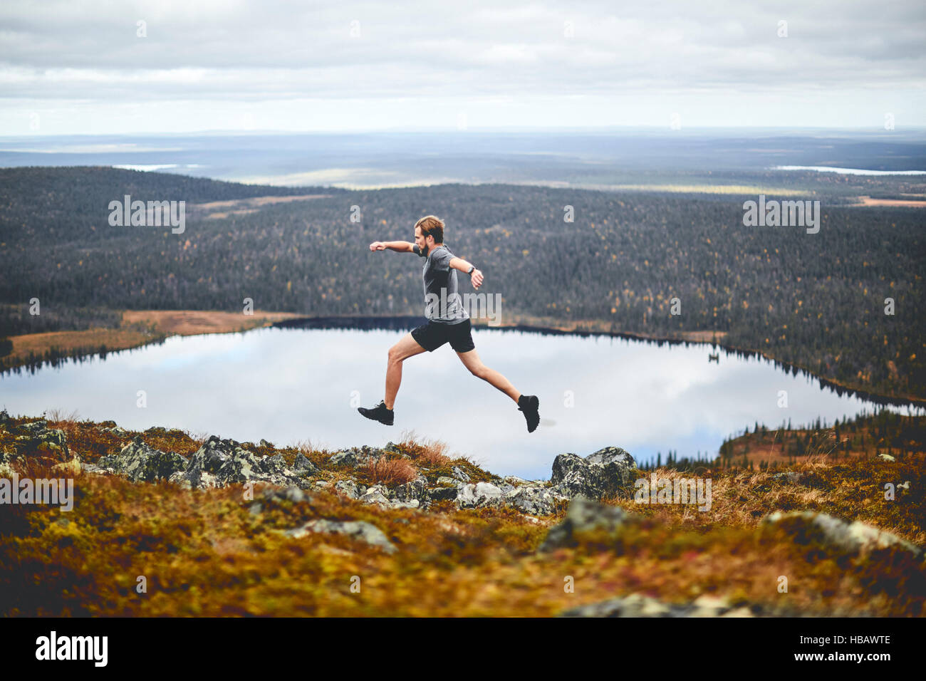 Mann sprinten auf felsigen Klippe, Keimiotunturi, Lappland, Finnland Stockfoto