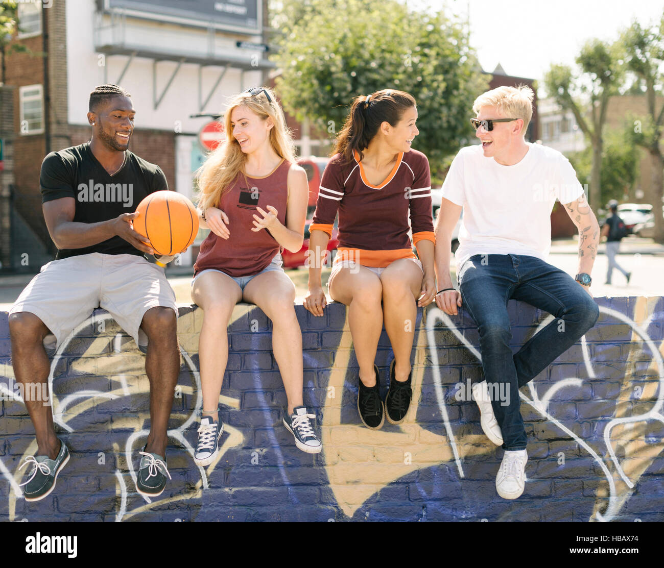 Männlichen und weiblichen Basketball Freunde sitzen plaudernd in Stadt Skatepark Stockfoto