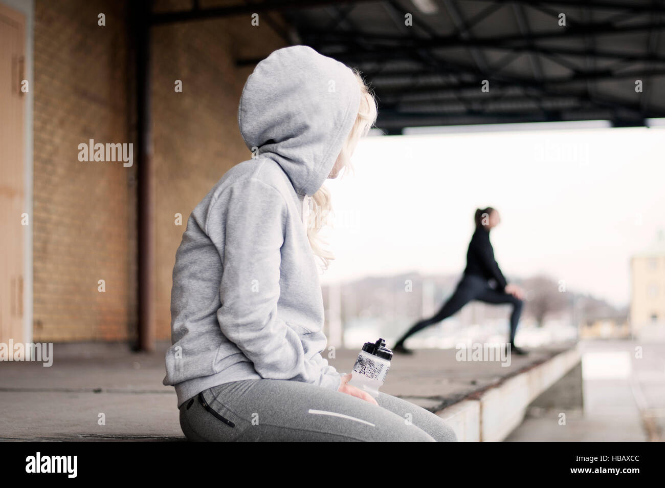 Weibliche Läufer beobachten Freund Aufwärmen außerhalb Lager Stockfoto