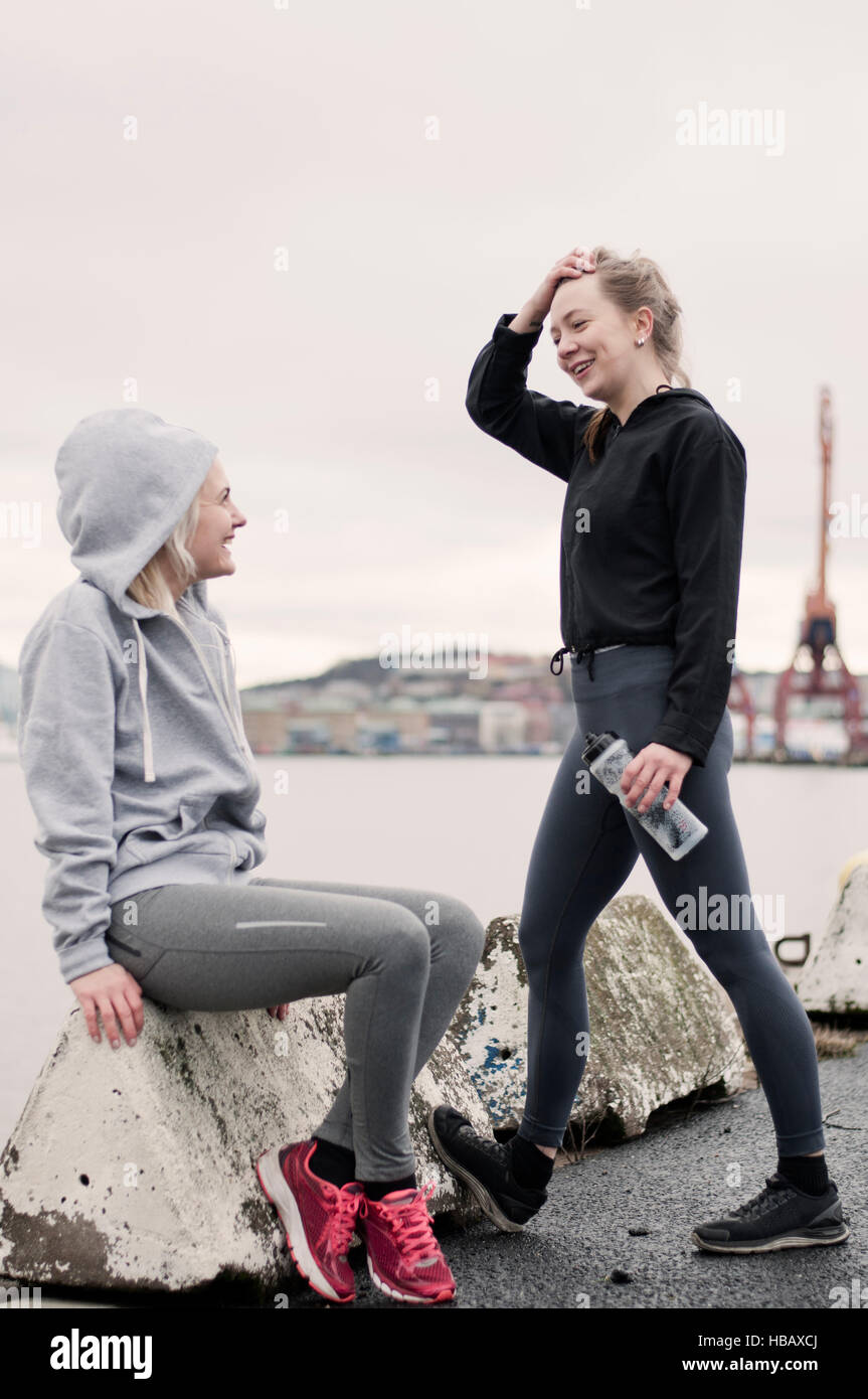Zwei laufende Freundinnen chatten im Hafen Stockfoto