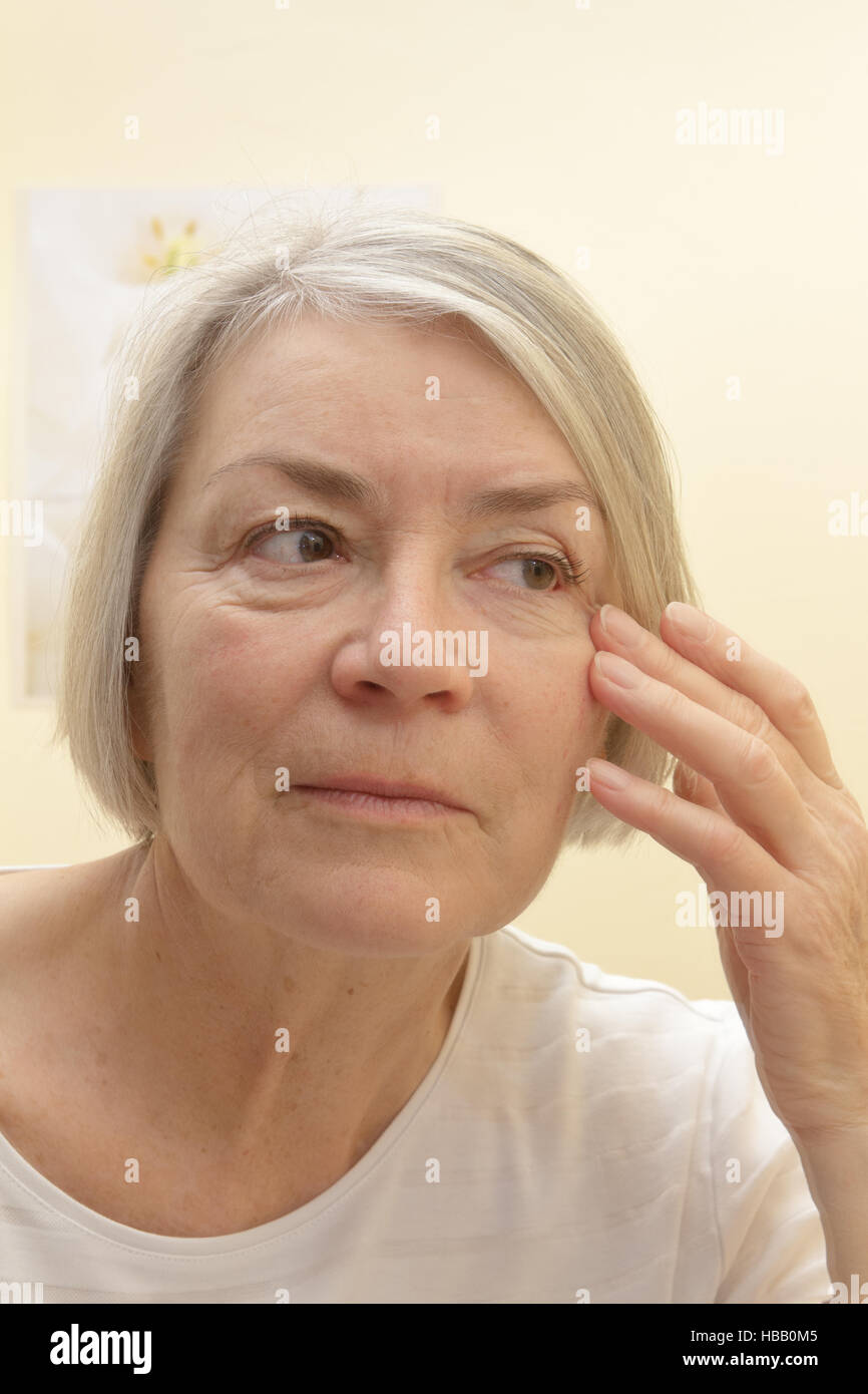 Alte Frau mit grauen Haaren, die Prüfung der Falten Gesicht Closeup portrait Stockfoto
