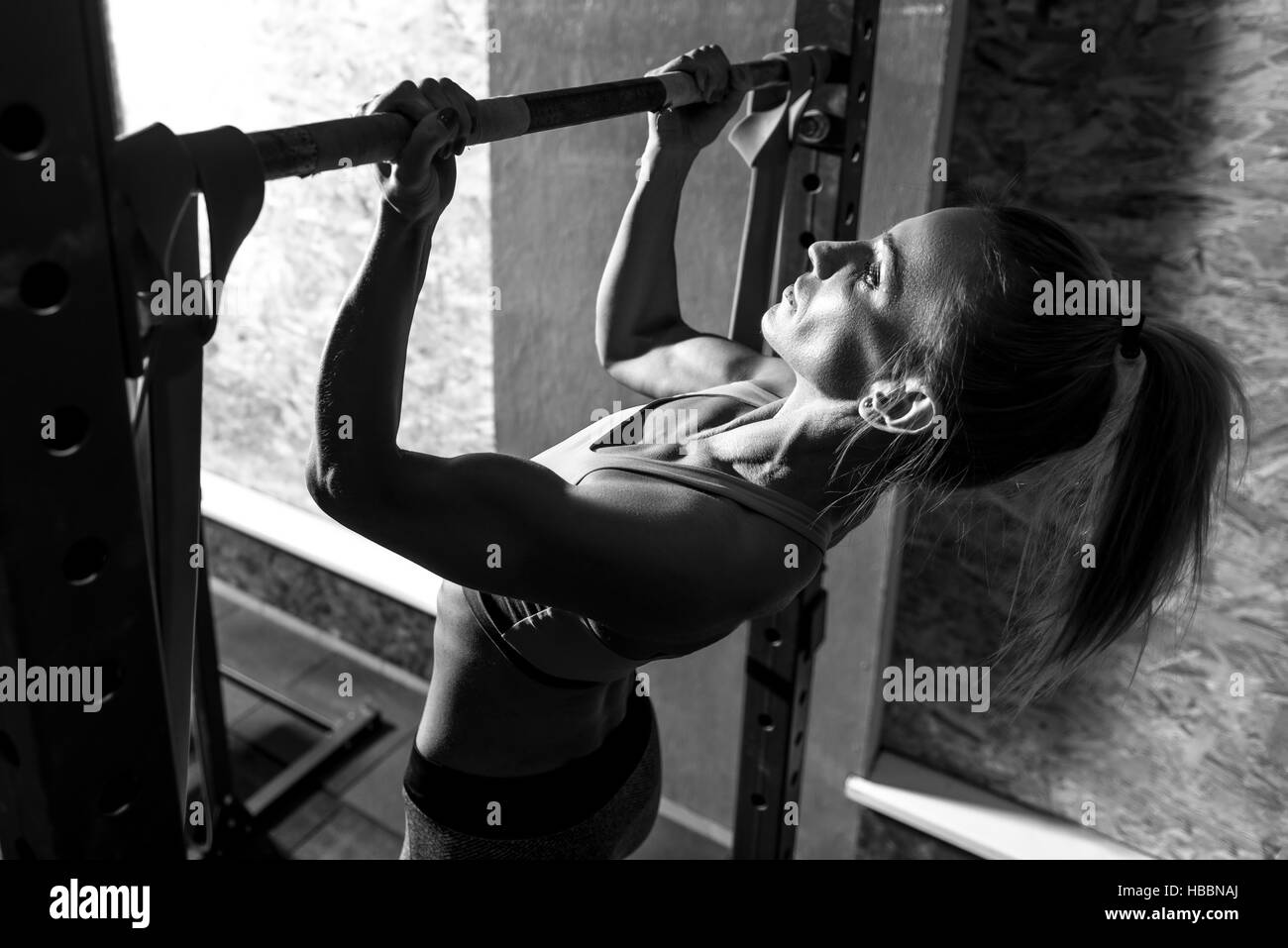 Schlank, gut gebaut Frau hält einen horizontalen Balken Stockfoto