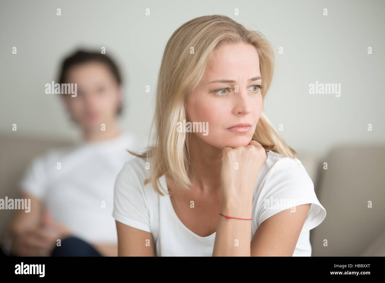 Schwere traurige Frau denken über ein Problem, Mann sitzt beiseite Stockfoto