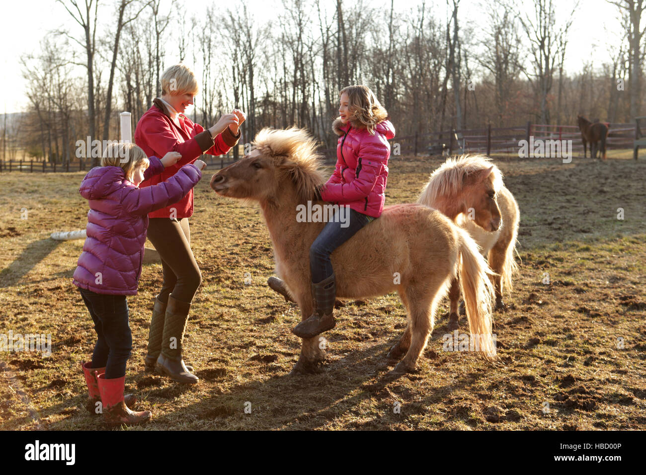 Junges Mädchen reiten, Pony, Mutter und Schwester, die neben ihnen stehenden Stockfoto