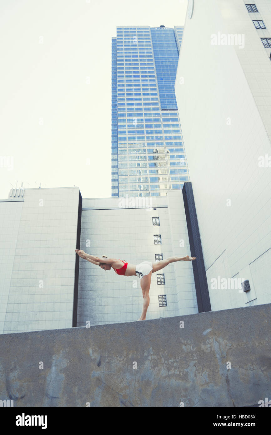Junge Frau im Außenbereich, an Wand in Yogaposition Stockfoto