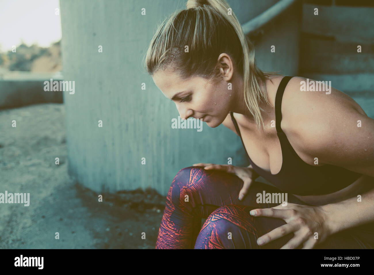 Junge Frau im Sport Kleidung, sitzen in urbaner Umgebung Stockfoto