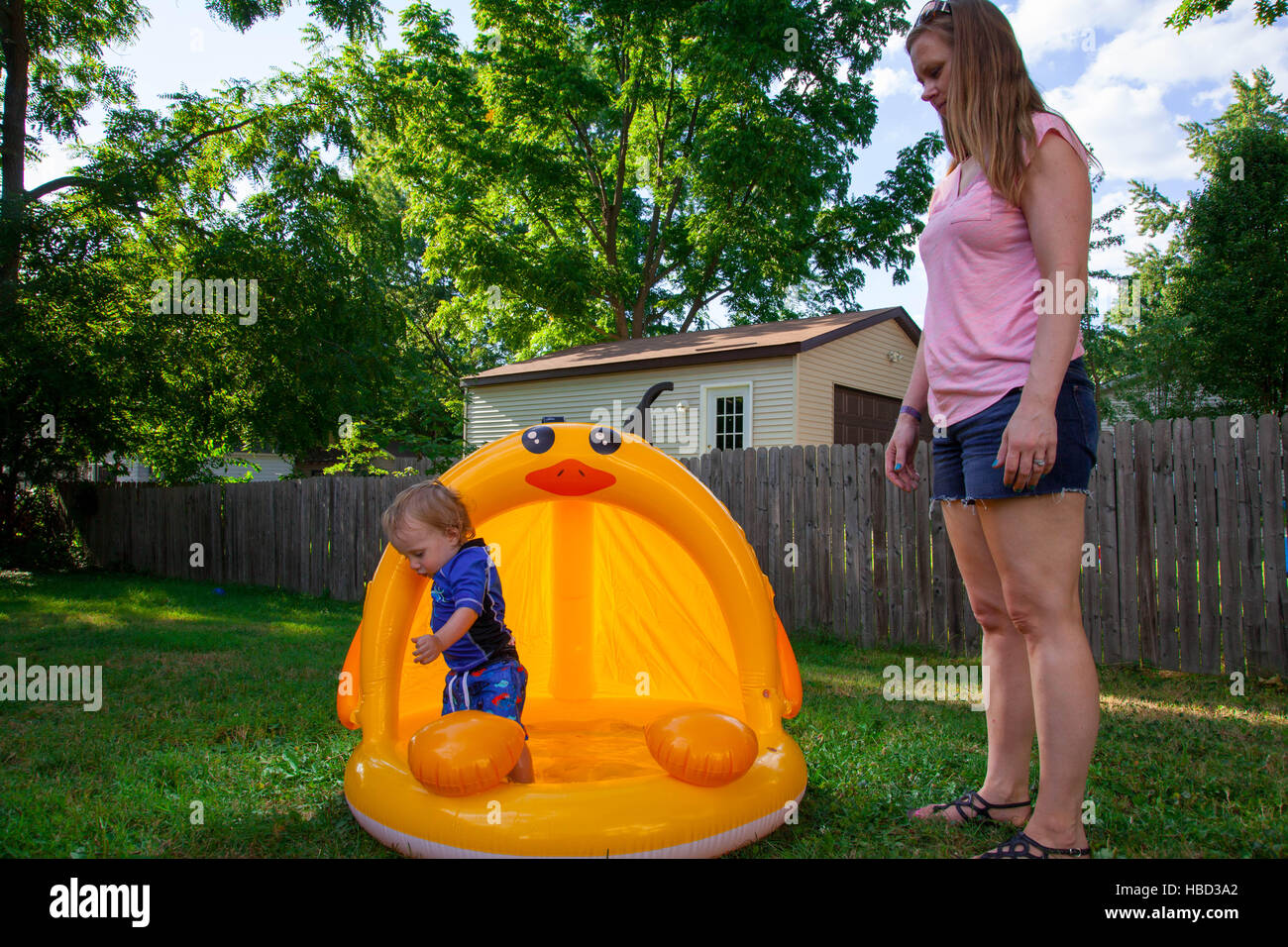 Caucasian Mother and Son spielen in und um ihren Hinterhof aufblasbaren pool Stockfoto