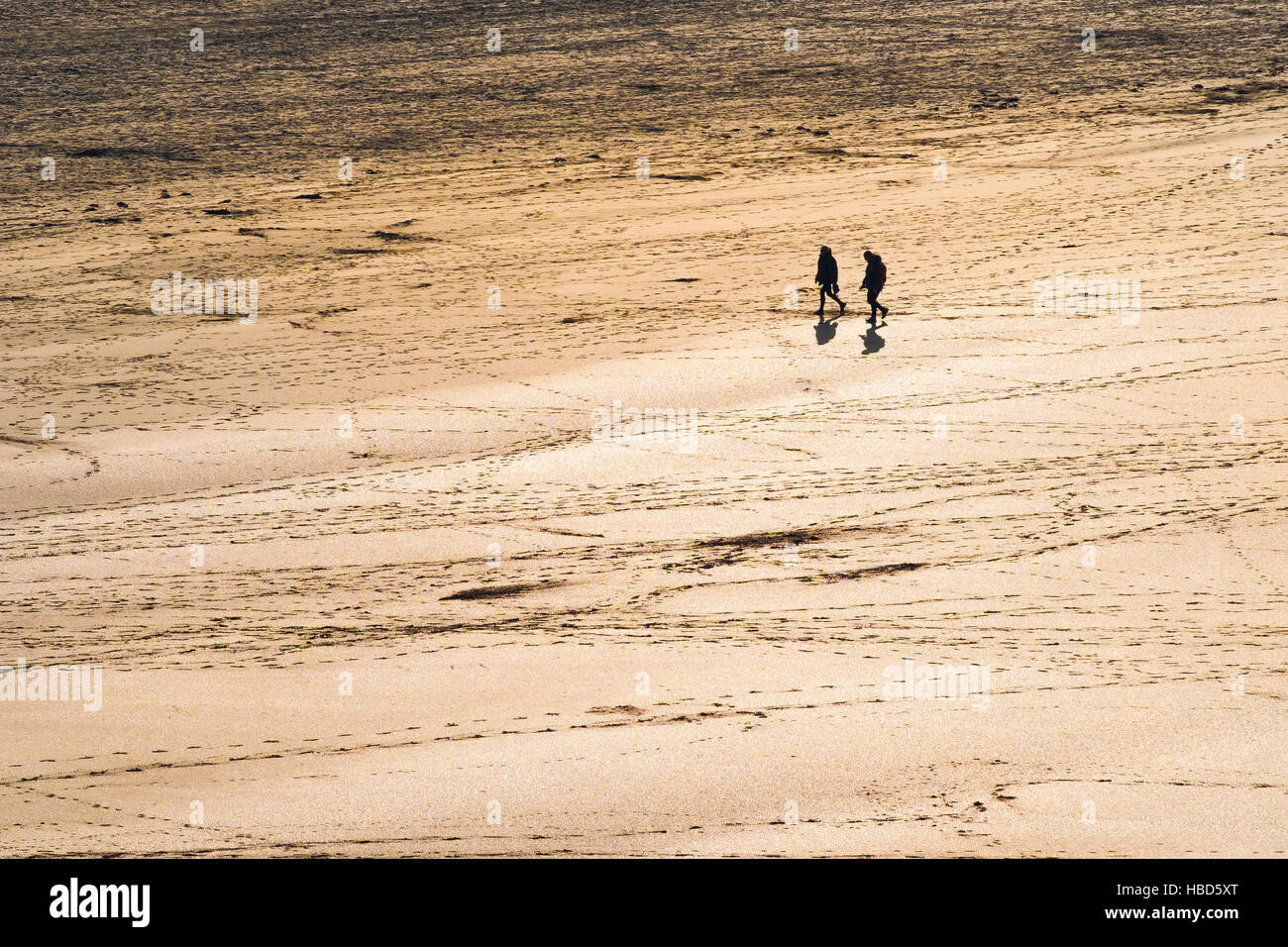 Zwei Personen gesehen, in der Silhouette und aus der Ferne auf dem preisgekrönten Crantock Beach in Newquay, Cornwall. Stockfoto
