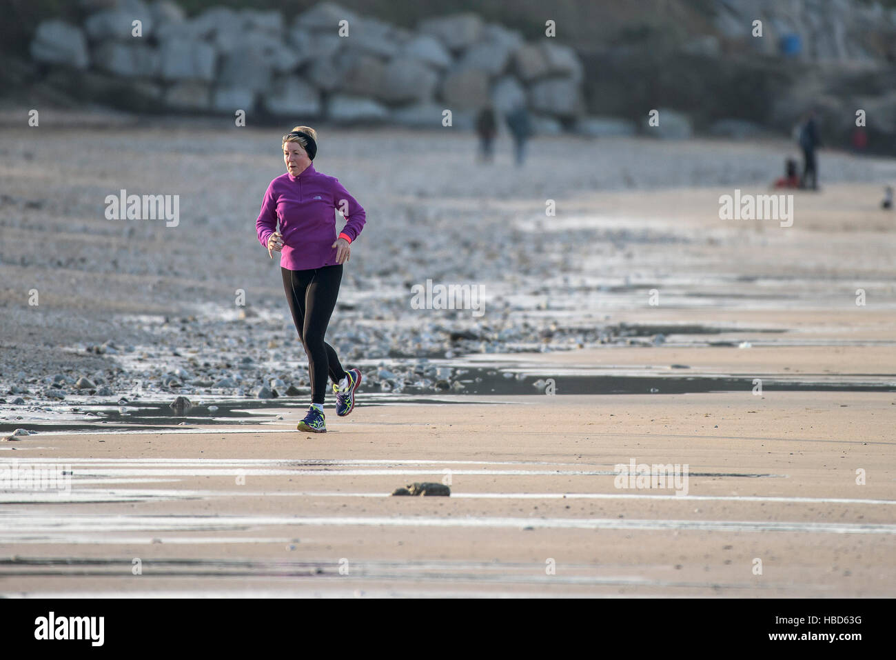 Eine reife Frau joggen entlang Fistral Beach in Newquay, Cornwall, England, Großbritannien. Stockfoto