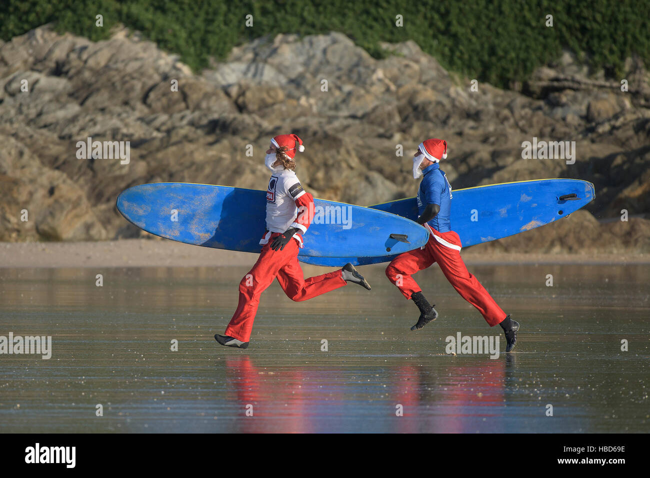 Surfen Weihnachtsmänner laufen am Strand entlang in den jährlichen Geldbeschaffung Santa Surfen Wettbewerb auf einem sehr kühl Fistral Beach in Newquay, Cornwall. Stockfoto