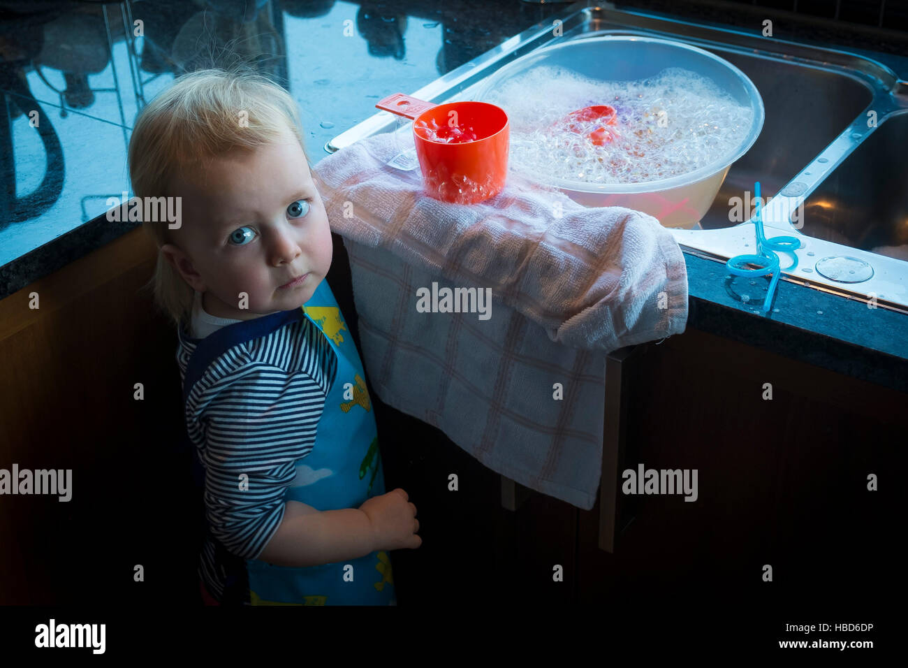 Ein Kleinkind suchen besorgt, als sie mit Luftblasen und Wasser spielt. Stockfoto