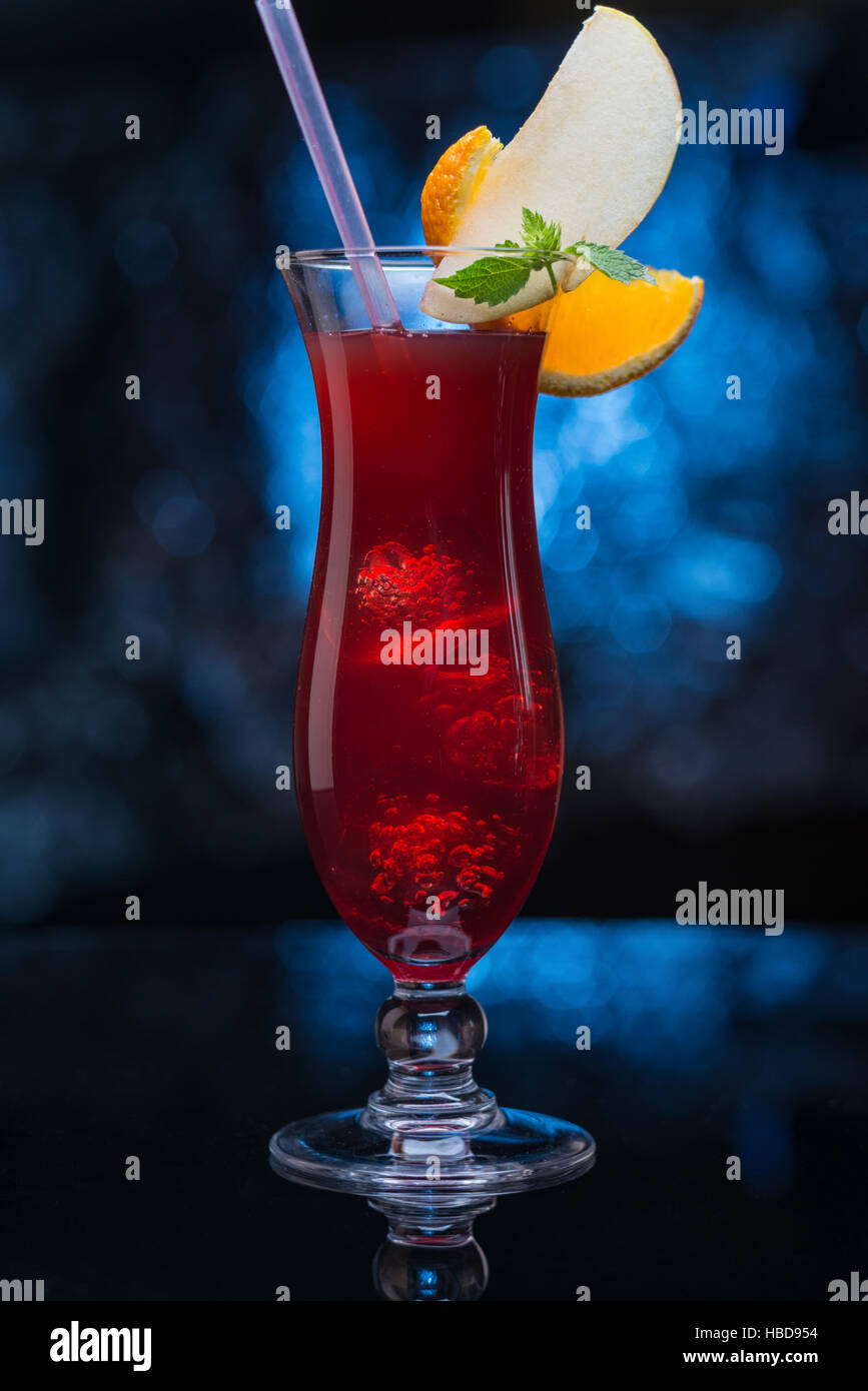 Köstliche rote cocktail garniert mit Früchten auf blauem defokussierten Hintergrund Stockfoto