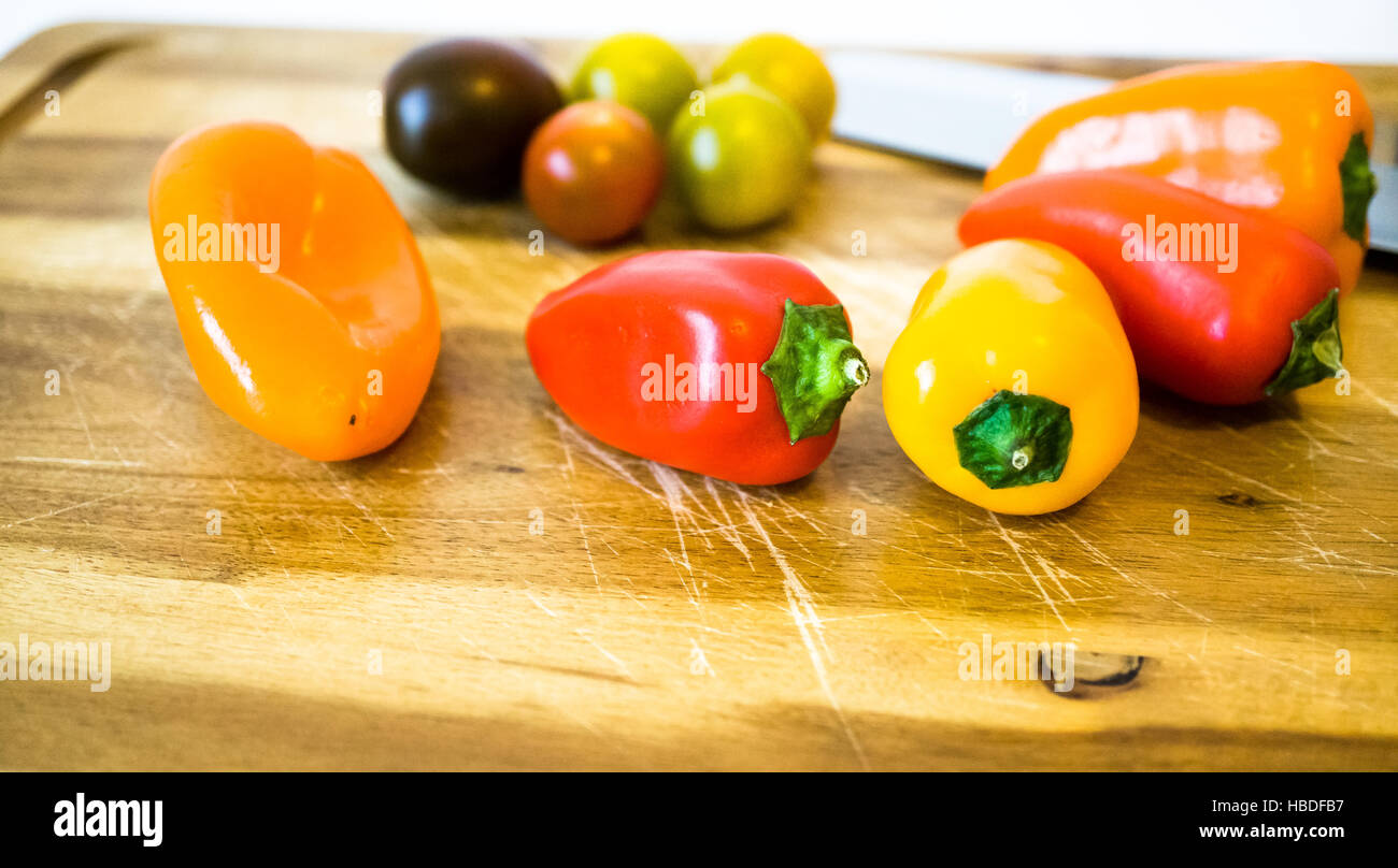 gemischte Paprika und Tomaten auf einem Schneidebrett Stockfoto